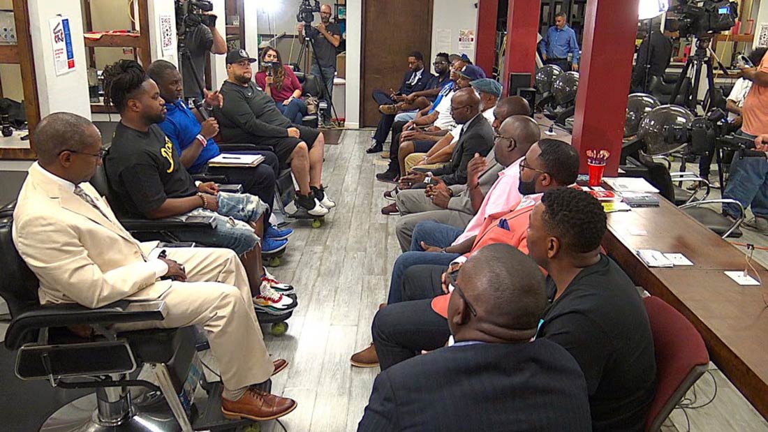 A group of people sitting in a beauty shop as a crew films