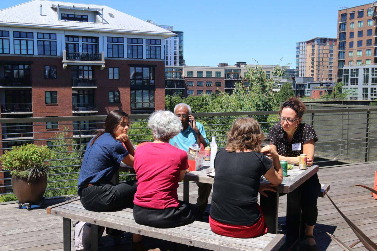 Six people sitting at a table on a rooftop deck