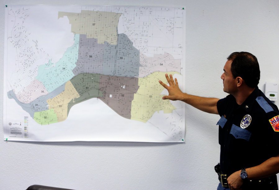 A police officer holds their hand in front of a color coded map