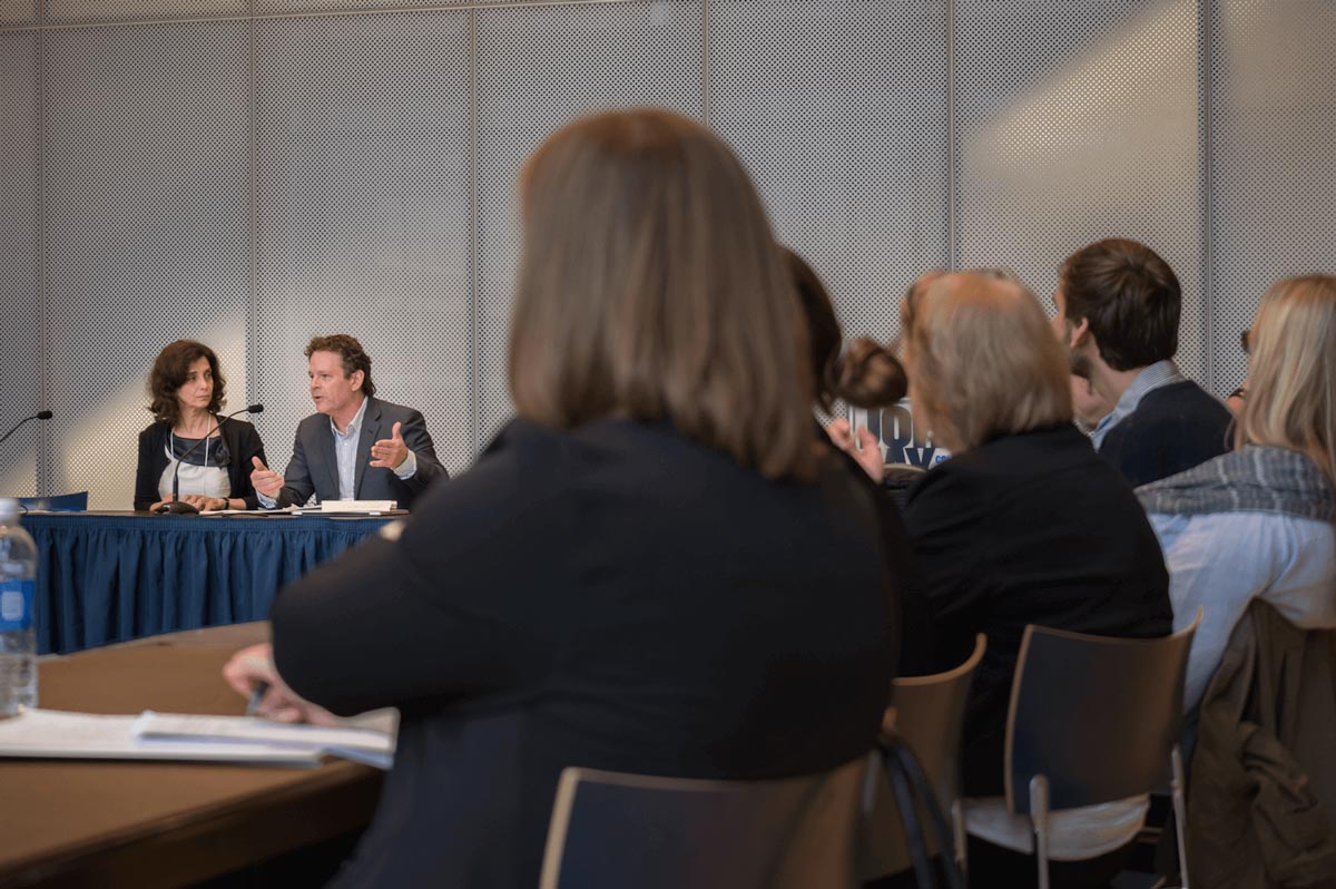 A person in a gray suit speaks at a conference