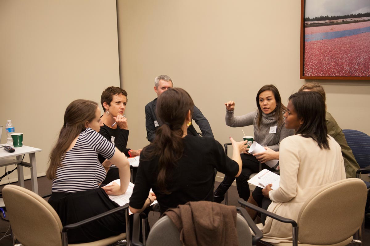 Seven people sitting in a group of circled chairs, having a discussion