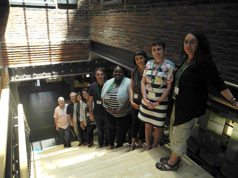 Nine people standing on a staircase, each on a single step