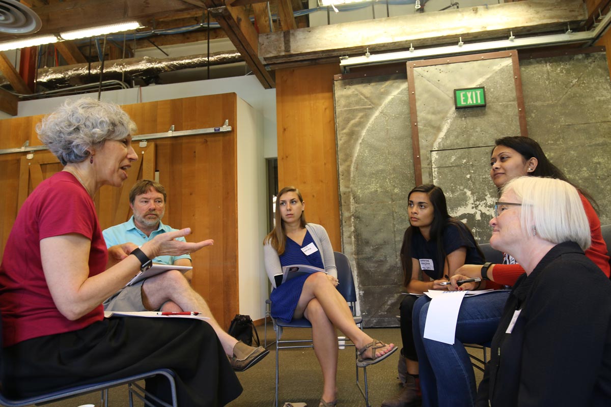 Six people sitting in a circle of chairs having a discussion