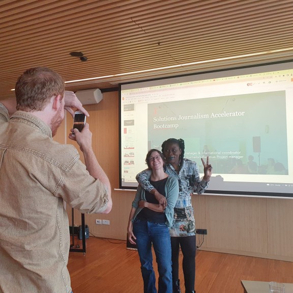 EJC event participants pose - one takes a photo of two people hugging and showing a peace sign