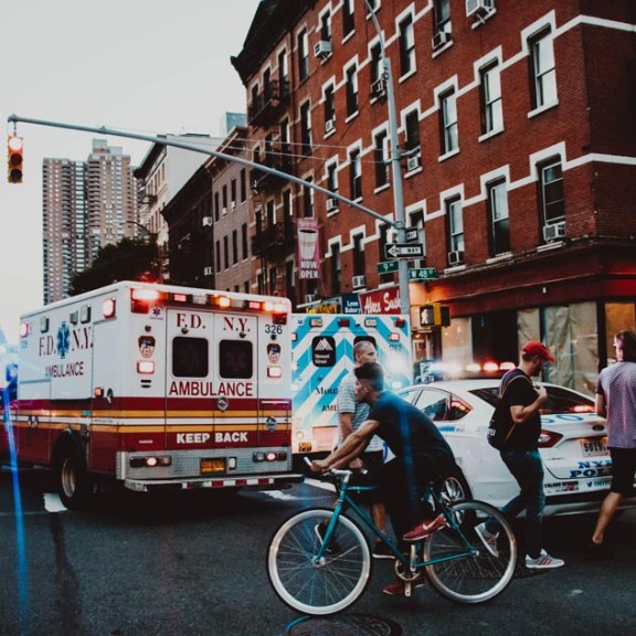 two ambualnces and one poilice cruiser parked on a city corner