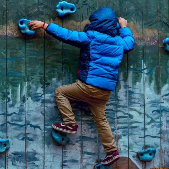 A young person scales a climbing wall