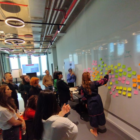 Journalists put sticky notes on a whiteboard during the Bridging News Fellowship kick-off meeting.