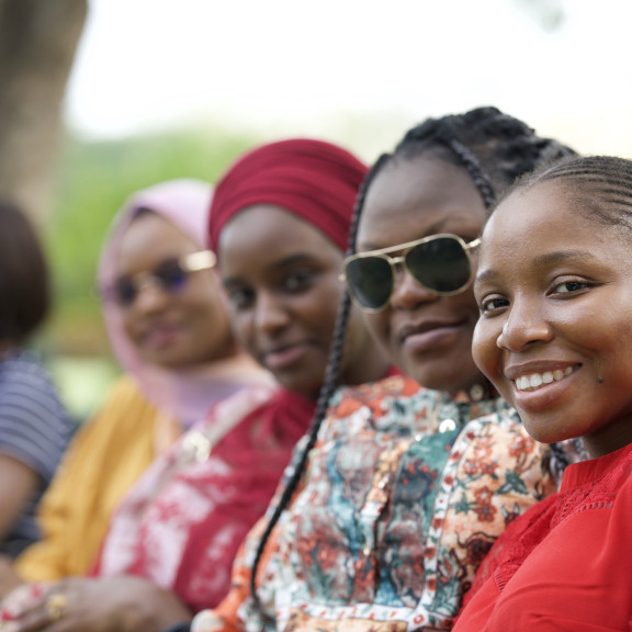 4 women in a row smiling at the camera