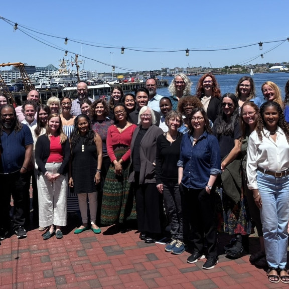 The SJN team poses outside with water in the background