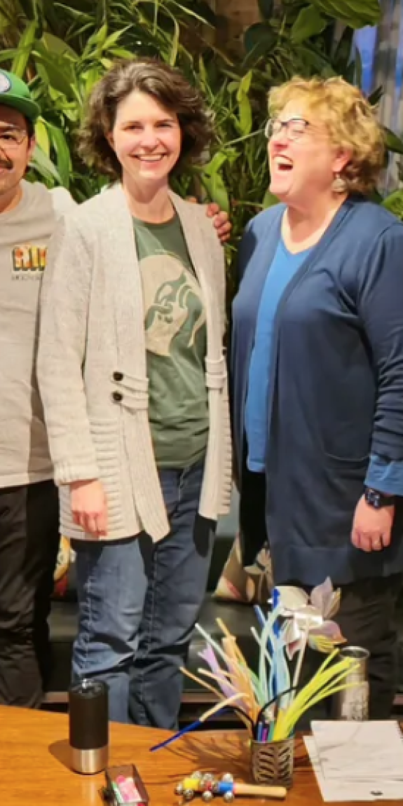 Five people stand together with arms around each other