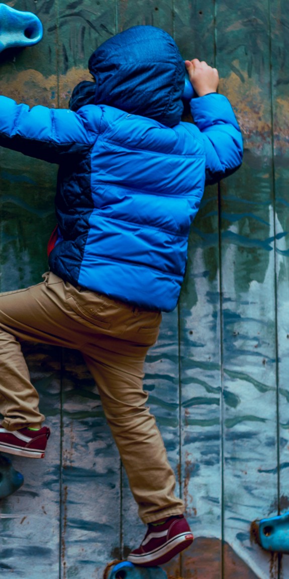A young person scales a climbing wall