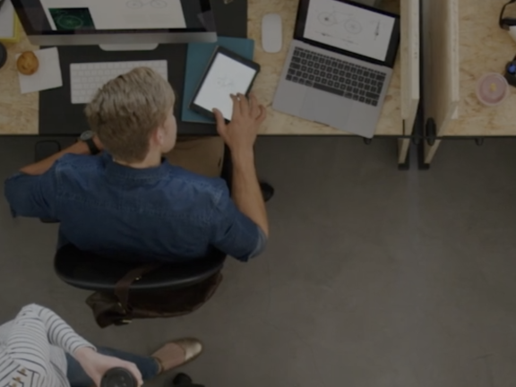 Aerial view of two people working on computers and tablets