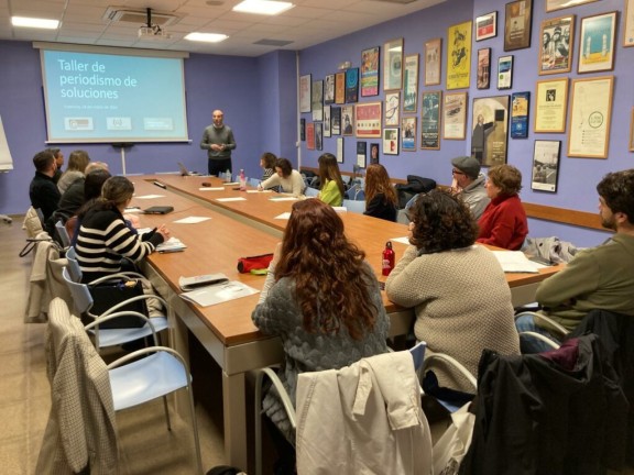 People gather around a table for a solutions journalism workshop