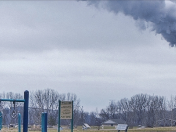 Smoke emerges from a tall tower next to a playground