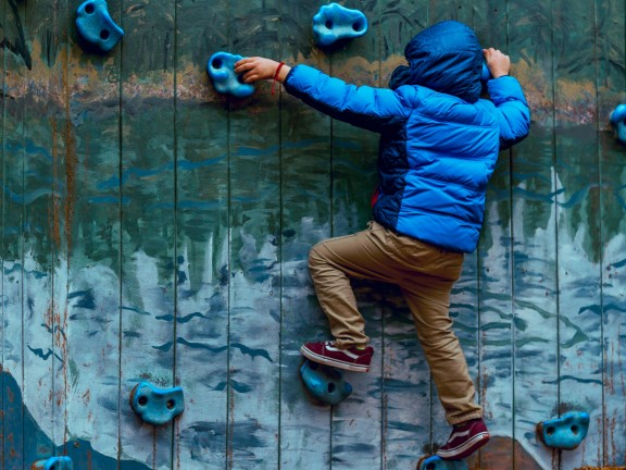 A young person scales a climbing wall