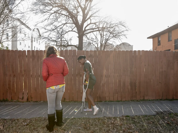 A young woman walks with crutches down a sidewalk
