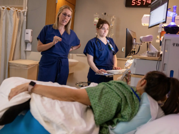 Medical staff speak with a woman in a hospital bed