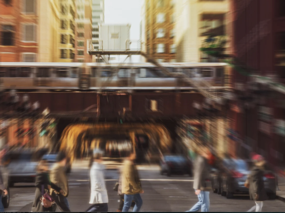 A blurred photo shows people crossing a city street