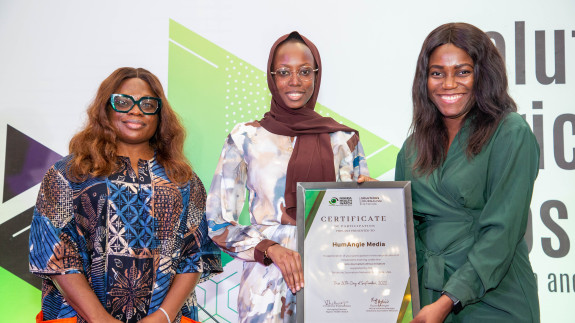3 women smiling where 2 women are holding up a plaque