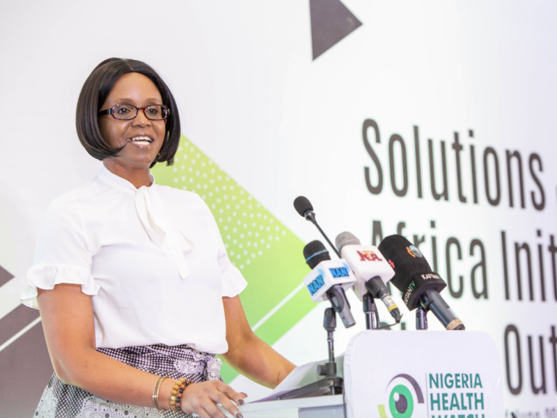 A woman speaks at a podium with Solutions Journalism Africa Initiative written on the presentation behind her