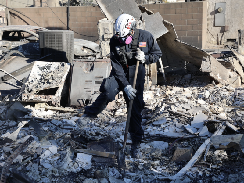 A person in protective gear sifts through debris after the Eaton Fire in Los Angeles County. Photo: CAL FIRE_Official via Flickr Creative Commons