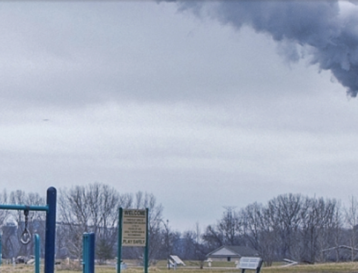 Smoke emerges from a tall tower next to a playground