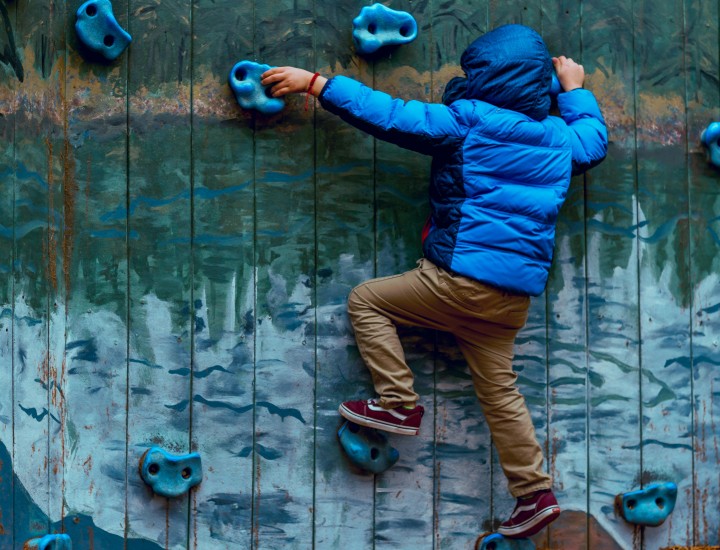 A young person scales a climbing wall