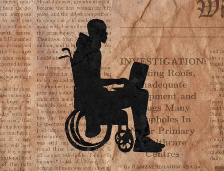 A man in a wheelchair works on a laptop with newsprint in the background