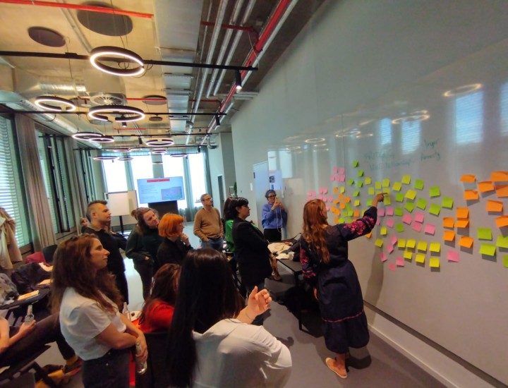 Journalists put sticky notes on a whiteboard during the Bridging News Fellowship kick-off meeting.