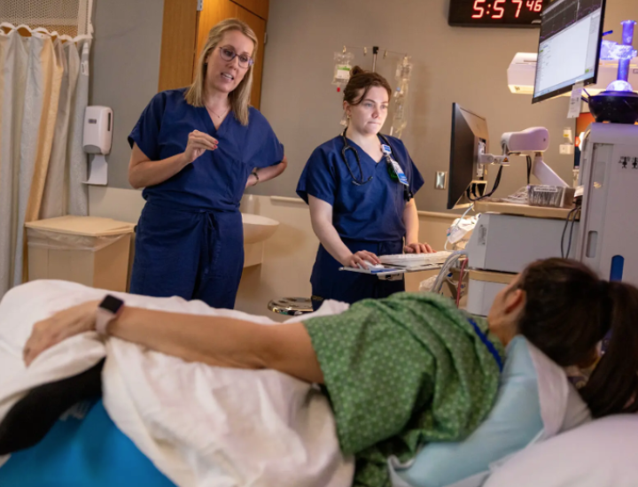 Medical staff speak with a woman in a hospital bed