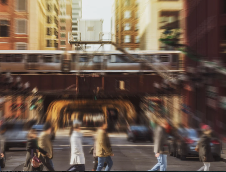 A blurred photo shows people crossing a city street