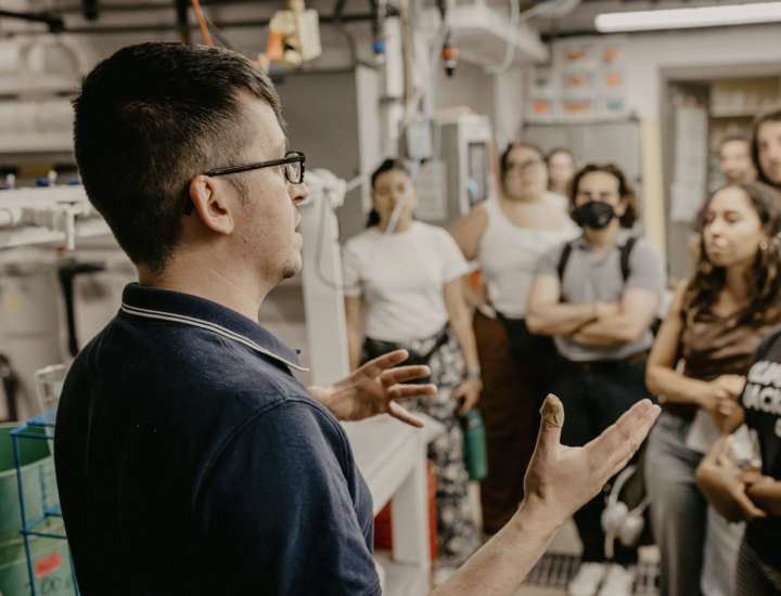 A man speaks to a group of journalists