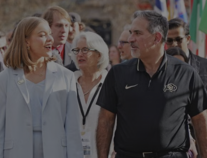 People talk while walking through a path lined with flags