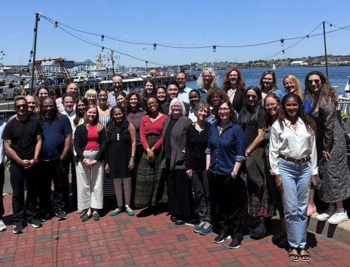 The SJN team poses outside with water in the background